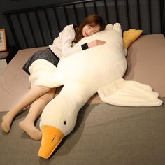 a woman laying on top of a bed next to a large stuffed duck