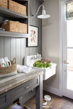 a bathroom sink sitting under a window next to a wooden shelf filled with towels and other items