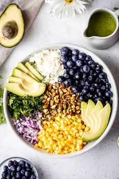 a bowl filled with blueberries, corn, avocado, and other vegetables