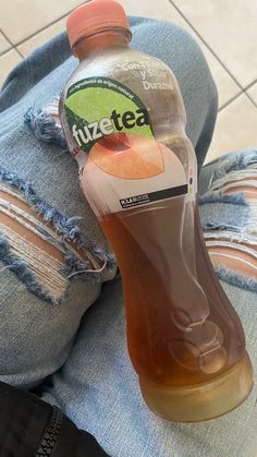 a bottle of juice sitting on someone's legs