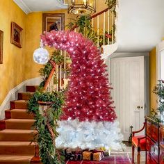 a red and white christmas tree sitting on top of a stair case next to a banister