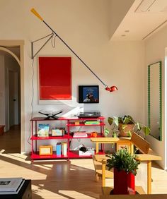 a living room filled with furniture and a red shelf next to a tv on top of a wooden table