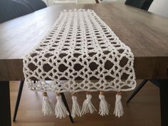 a crocheted table runner with tassels sits on a dining room table