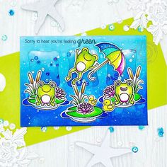 a greeting card with two frogs and an umbrella in the water on top of a green plate