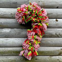 a red and green wreath hanging on the side of a wooden wall