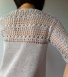 a woman wearing a white top with crochet on it