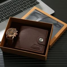 a watch and wallet sitting in a box next to a laptop