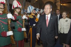 a man in a suit and tie standing next to soldiers