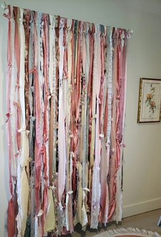 the curtain is covered with ribbons in various colors and sizes, along with pictures on the wall