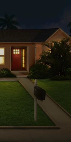 a house that is lit up at night with the lights on and grass in front