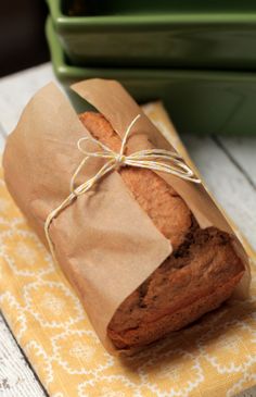 a piece of bread wrapped in brown paper sitting on top of a yellow and white napkin