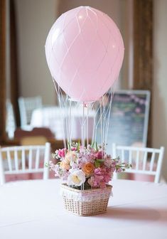 a basket filled with flowers sitting on top of a table next to a pink balloon