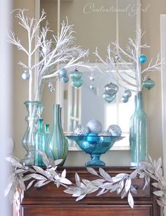 a blue and white christmas decoration on a mantle with silver branches in front of it