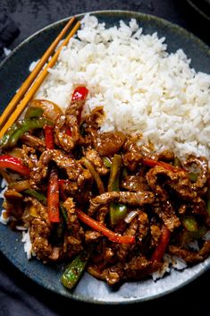 a plate full of rice and meat with chopsticks