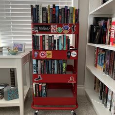 there is a red cart with many books on it in front of some shelves full of books