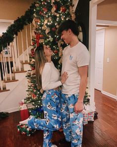 a man and woman standing in front of a christmas tree