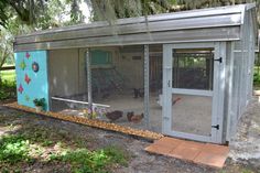 a chicken coop in the middle of a yard with two chickens inside and one laying on the ground