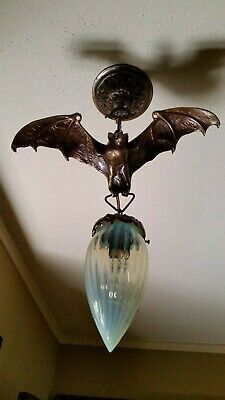 a light fixture with a bat hanging from it's ceiling