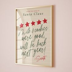 a christmas card hanging on the wall with santa claus written in red and green stars