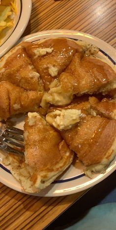 a white plate topped with pancakes covered in caramel sauce and butter on top of a wooden table