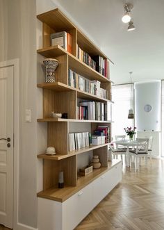 a bookshelf with many books on it in the middle of a living room