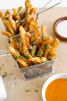 french fries with parmesan cheese and herbs in a basket next to dipping sauce