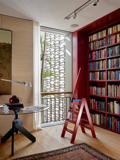 a room with bookshelves and a ladder in the corner next to a table