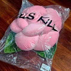 a pink stuffed animal wrapped in plastic on top of a wooden floor with the word kiss written on it