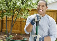 a smiling man holding a garden tool in his hands