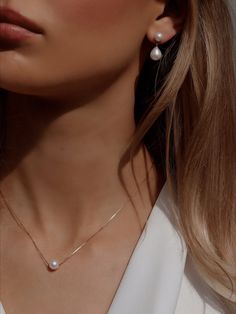 a close up of a woman wearing earrings and a necklace with white pearls on it