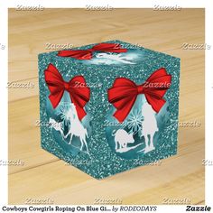 a blue gift box with red bows and reindeer silhouettes on the front, sitting on a wood floor