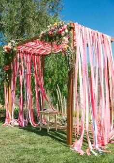 an outdoor wedding ceremony with pink and white streamers hanging from the chute at the end of the aisle