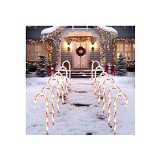 candy canes are lined up in front of a house with christmas lights on it