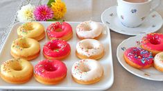 there are many doughnuts on the tray next to a cup and saucer