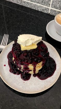 a white plate topped with pancakes covered in blueberry sauce