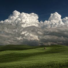 a green field with some clouds in the sky