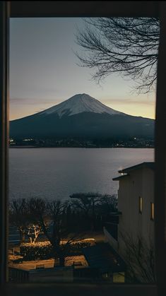 a view of a mountain and the ocean at dusk from inside a window in a house