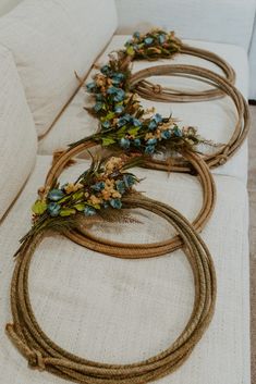 four rope wreaths with flowers on them sitting on a couch