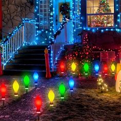 christmas lights are on the ground in front of a house with stairs and trees lit up