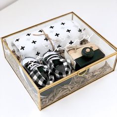 a glass box with black and white items in it on top of a table next to a pillow