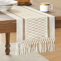 a table runner with tassels on it and a coffee cup in the background