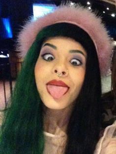 two women with green hair are taking a selfie in front of the camera and one is sticking out her tongue