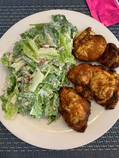 a white plate topped with chicken and a salad