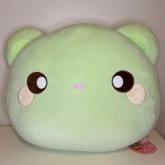 a large green stuffed animal sitting on top of a white table next to a wall