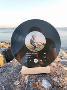 an mp3 player sitting on top of a rock next to the ocean with a woman's face