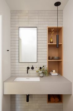 a bathroom with a sink, mirror and shelving unit in the wall above it