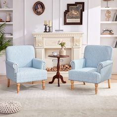 two blue chairs sitting next to each other in front of a fireplace