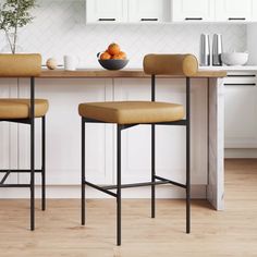 two brown stools sitting in front of a kitchen counter with fruit on top of it