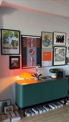 a living room with pictures on the wall and a green cabinet in front of it