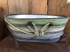 a woven basket is sitting on top of a brown cloth covered tablecloth, with two handles tied at the bottom